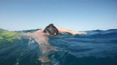 Swimmer in the ocean with high waves and yellow costume trains.