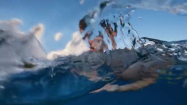 Boy swims frog style in open ocean.
