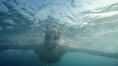 Boy struggling to swim in rough sea.