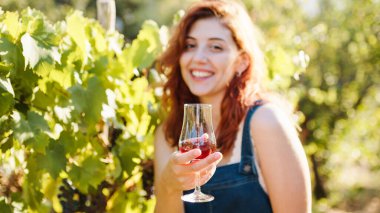 Young beautiful girl with goblet of red wine near the vineyards with quality grapes