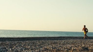 Sarı kostümlü adam şafakta sahilde eğlenir. El kamerasıyla çekim 