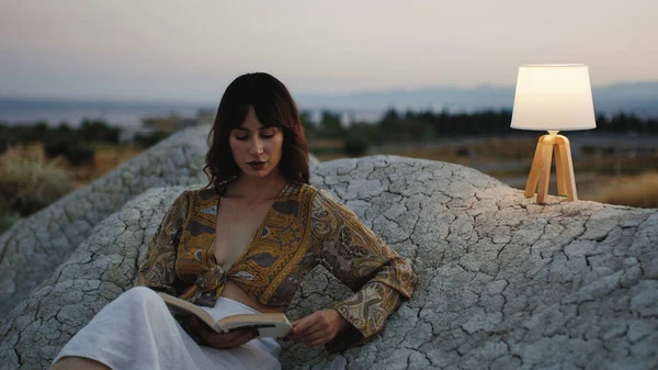 Beautiful girl enjoy the sunset on the mountain in the evening with abat jour lamp on the stones