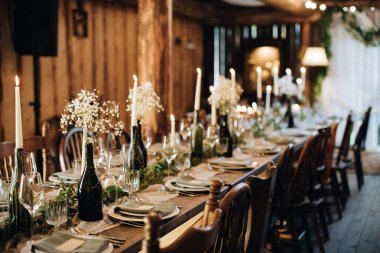 Noel yemeği için bir düğün masasını mumlar ve çiçeklerle süslemek.