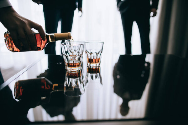 A man pours whiskey into glasses for his friends