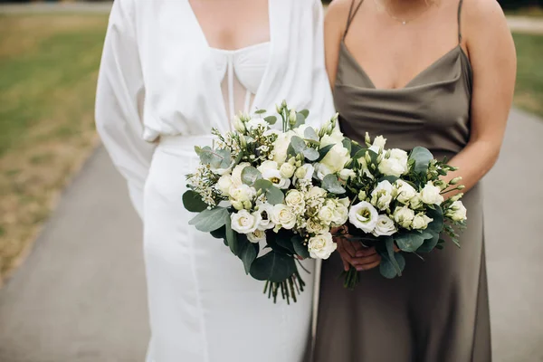 花嫁と彼女の友人は白いバラの結婚式の花束を持っています — ストック写真