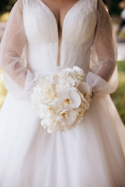 白いドレスの花嫁は 白い蘭の豪華な花束を保持しています — ストック写真