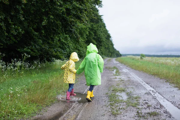 Dua Adik Kecil Dengan Jas Hujan Melompat Genangan Air Jalan — Stok Foto