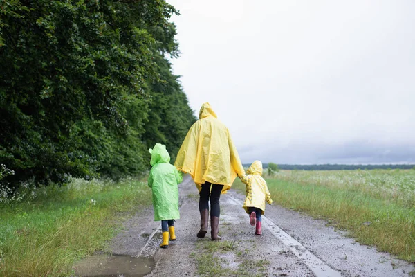 Matka Dwoje Dzieci Siostry Płaszczach Przeciwdeszczowych Spacerują Deszczu Naturze Wiosenny — Zdjęcie stockowe