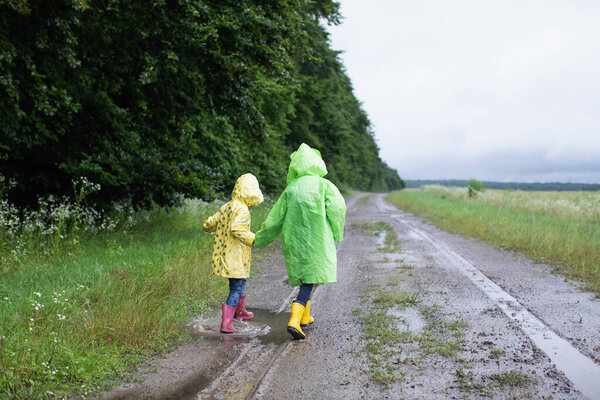Two Little Sisters Raincoats Jump Puddles Road Stock Picture