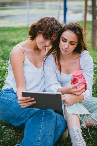 Dvě Dívky Sledují Video Tabletu Zatímco Sedí Trávě — Stock fotografie