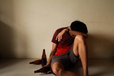 Bira şişeli sarhoş adam hayatında stres yaşıyor ve boş bir odada yalnız başına oturuyor, üzgün, yalnız, toyluk, ergenlik çağında, ev içi şiddet, istenmeyen aşk sorunları, yalnız, aile.