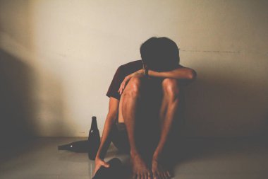 Bira şişeli sarhoş adam hayatında stres yaşıyor ve boş bir odada yalnız başına oturuyor, üzgün, yalnız, toyluk, ergenlik çağında, ev içi şiddet, istenmeyen aşk sorunları, yalnız, aile.