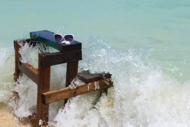 Güneş gözlüğü ve deniz kabukları. Sandalyeye de deniz dalgaları çarpmış. Yazın tatil.