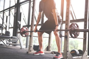Spor salonunda halterle eğitime başlayan genç adam. Fitness kaslı vücut. Fitness konsepti. Egzersiz konsepti