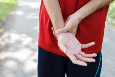 Antrenman konseptinden kaynaklanan sakatlık ve spor konsepti yüzünden acı veren bileğini tutan erkek kollarına yakın çekim..
