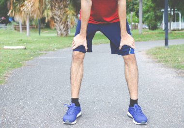 Yorgun genç koşucu koşudan sonra dinleniyor. Egzersiz konsepti.