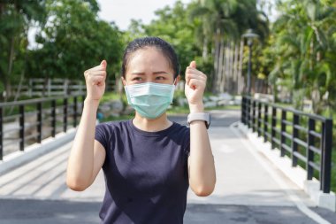 Tıbbi koruyucu maskeli genç kadın parkta dinleniyor. COVID19 'dan koruyucu maske kullanma kampanyası