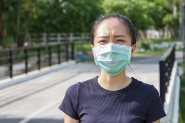 Tıbbi koruyucu maskeli genç kadın parkta dinleniyor. COVID19 'dan koruyucu maske kullanma kampanyası