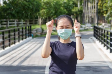 Tıbbi koruyucu maskeli genç kadın parkta dinleniyor. COVID19 'dan koruyucu maske kullanma kampanyası