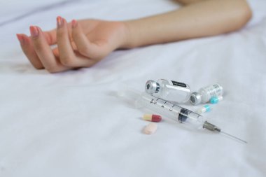 Uyuşturucu konsepti. Kadın, pasif elleri yatağa enjekte eden uyuşturucu bağımlıları. haplar ve enjeksiyon