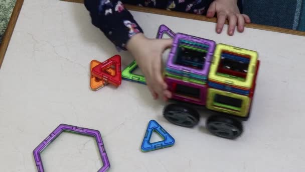 Kız Masanın Üzerindeki Manyetik Yapıcının Parçalarından Makinenin Bir Heykelini Yapıyor — Stok video