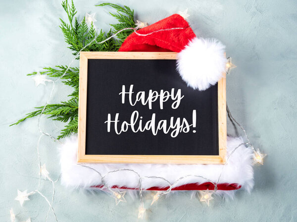 Счастливые каникулы на доске с шапкой санты и веточками фира