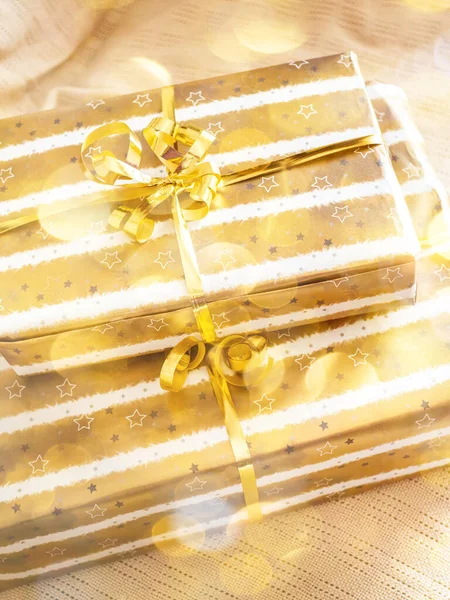 Pila di Natale di scatole regalo avvolte d'oro su plaid beige — Foto Stock