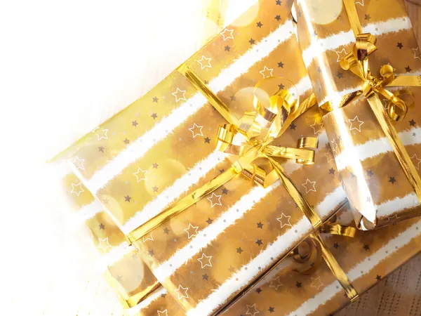 Weihnachtlicher Stapel goldverpackter Geschenkboxen auf beige kariertem Papier — Stockfoto