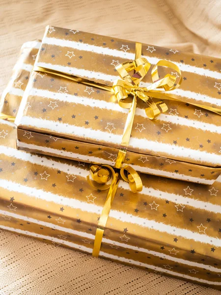 Christmas stack of golden wrapped gift boxes on beige plaid — Stock Photo, Image