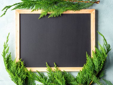 Ahşap çerçevedeki boş karatahta yazı, kış yeşili dallar