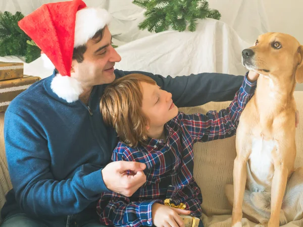 Папа и сын в шапках Санты и собаке на Рождество — стоковое фото