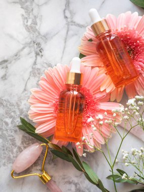 Kozmetik serum şişesi ve pembe kuvars suratlı patinaj masası.