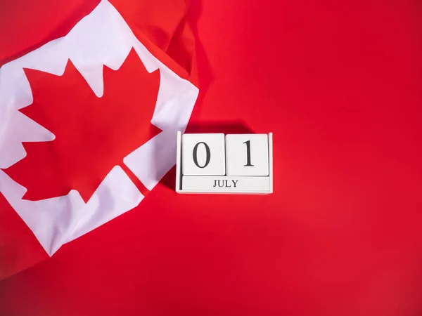 加拿大日概念与加拿大国旗碎片和7月1日日期在白色木制日历上的黑体字红色背景 — 图库照片