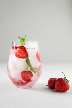 Çilekli ve naneli yaz kokteyli. Yaz için içecek ya da içecek, soğuk tatlı ve ekşi limonata ve beyaz arka planda dilimlenmiş taze çilek. Ferahlatıcı ve susuzluğu giderici bir kavram. .  