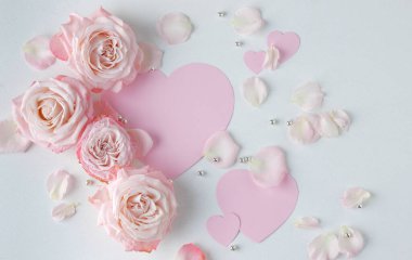 Sevgililer Günü geçmişi. Pembe çiçekli yaratıcı bir düzen, yumruklu pastel arka planda kağıt kalp. Bahar, yaz ya da bahçe konsepti. Kadın Günü hediyesi. Sevgililer Günü konsepti. Düz konum, üst görünüm, kopyalama alanı