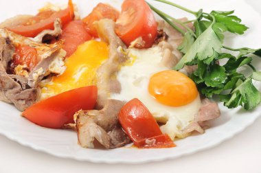 scrambled eggs with bacon and tomatoes in a plate with parsley