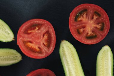 red tomatoes and cucumbers cut into halves - top view flat lay