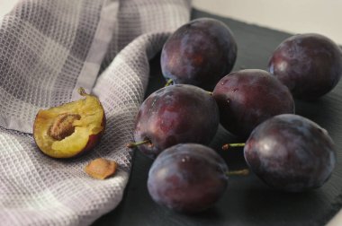 ripe plums on a black background - plum pulp and stone