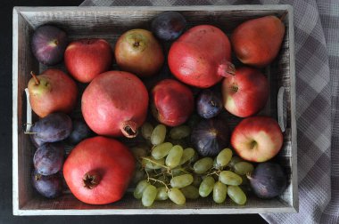 Fruit  on a wooden tray  - plums, pears,  grapes, pomegranate - autumn harvest - top view flat lay