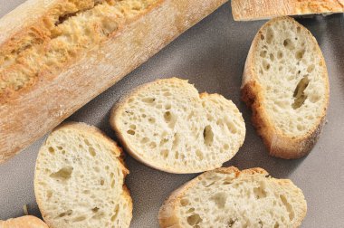 mini baguette whole and cut into pieces on ceramic background - french cuisine top view flat lay