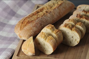mini baguette whole and cut into pieces on wooden background - french cuisine