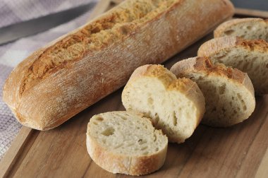mini baguette whole and cut into pieces on wooden background - french cuisine