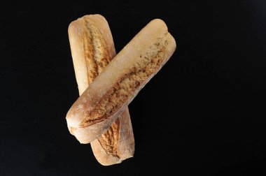 two mini baguettes on a black background - French cuisine - top view flat lay