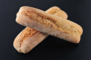 two mini baguettes on a black background - French cuisine