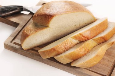 round bread cut into slices on a wooden board with a knife