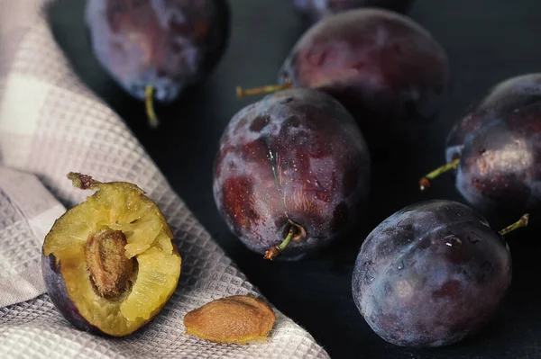 ripe plums on a black background - plum pulp and stone