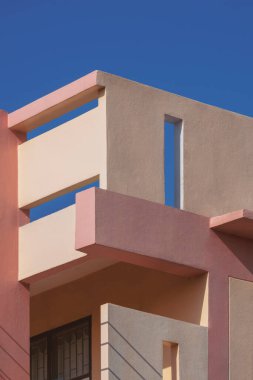 Düşük açı ve perspektif yan görünümü dikey çerçevede mavi berrak gökyüzüne karşı vintage pembe bina üzerindeki havalandırma blokları ile yüzgeç betonu gölgeleme