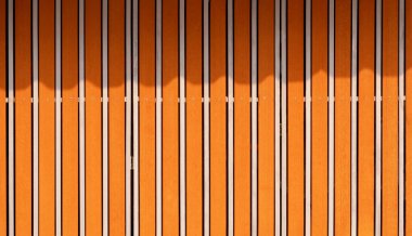 Ahşap ve paslanmaz çelikten yapılmış, güneş ışığı ve yüzeyinde gölgesi olan klasik sürgülü kapının arka planı