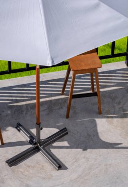 Beyaz şemsiyeli, ahşap sandalyeli, siyah çitli, antika kahve dükkanının terasında.