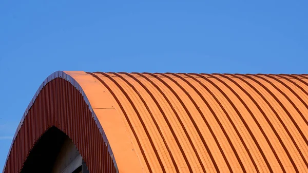 蓝色透明天空背景下橙色弯曲波纹钢制屋顶 — 图库照片